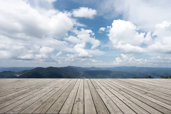 Empty wooden floor with green hill in cloud sky — Stock Photo, Image