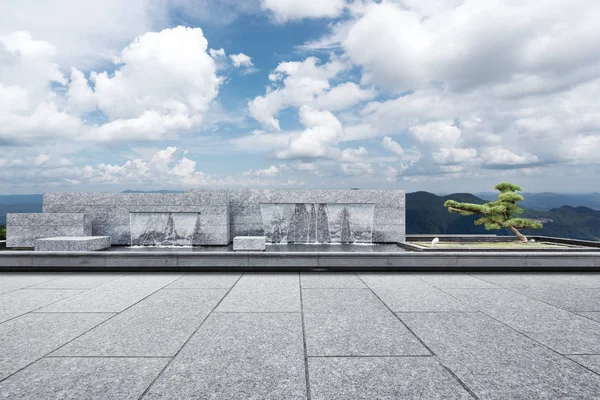 空大理石広場人工滝 雲空の緑の丘 — ストック写真