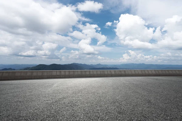 Пустая асфальтовая дорога с зеленым холмом в облачном небе — стоковое фото