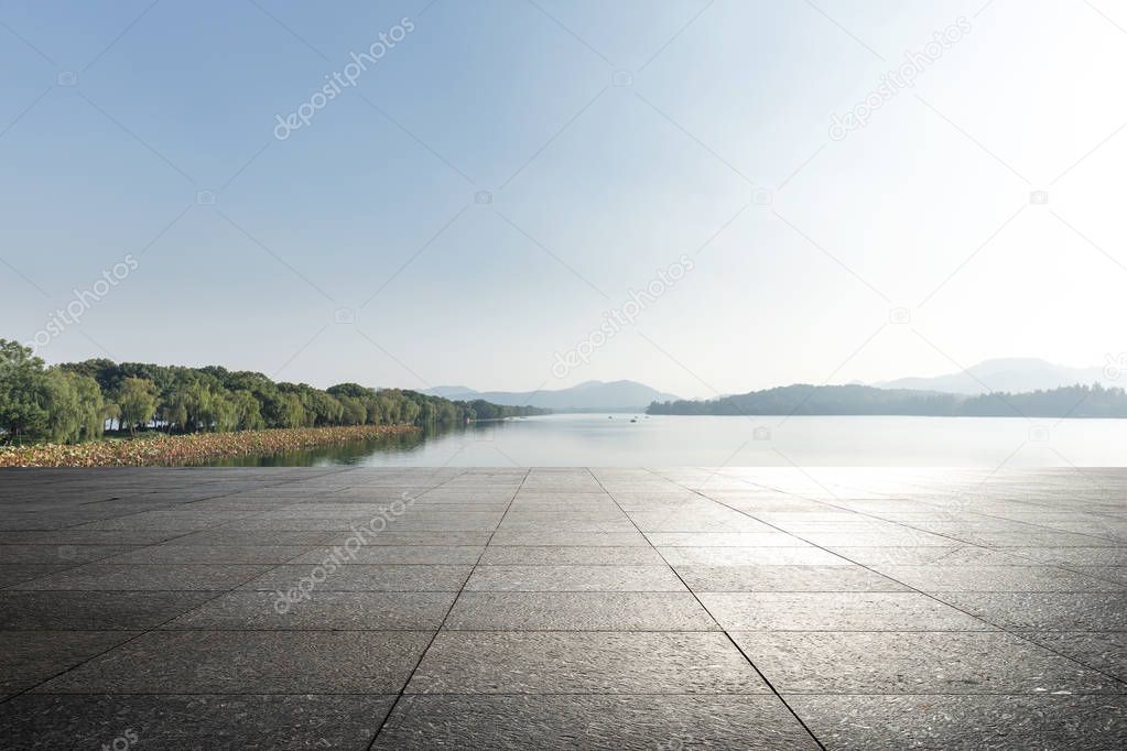 empty marble floor and beautiful lake in blue sunny sky