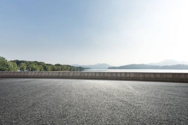 Mavi gökyüzü güneşli güzel göl yakınındaki boş asfalt yol