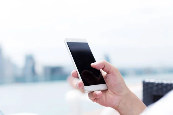 man plays with mobile phone on balcony in midtown of Kuala Lumpur