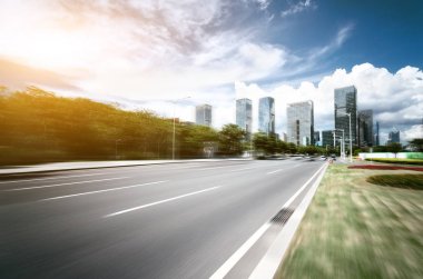 arka plan olarak gökdelenler ile modern bir şehir, asfalt yolu