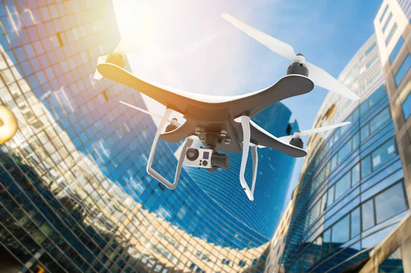 Drone com câmera digital voando em uma cidade moderna ao pôr do sol — Fotografia de Stock