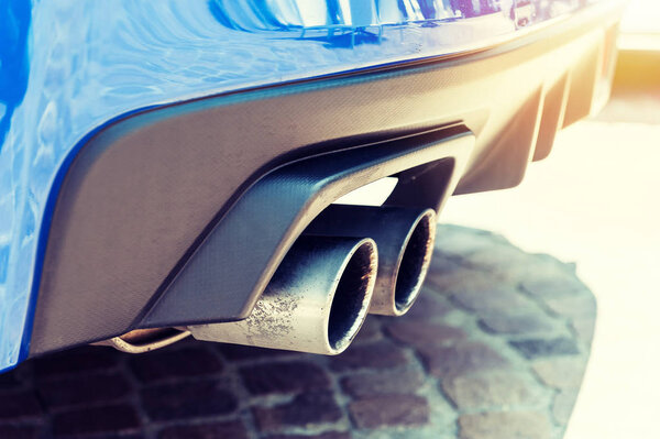 Close up of a car dual exhaust pipe in sunlight