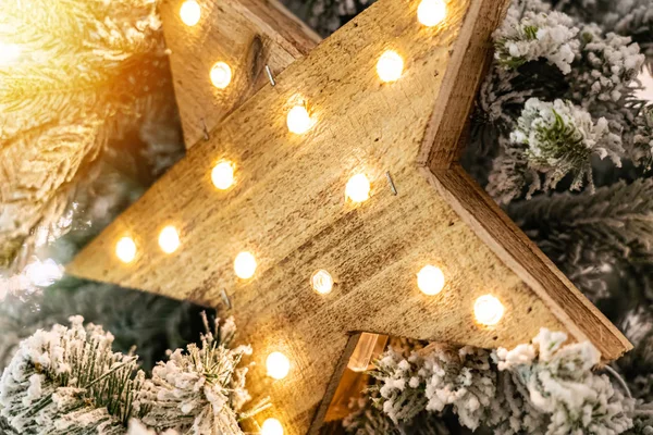 Estrella decorativa de madera con lámparas colgando de ramas de pino — Foto de Stock