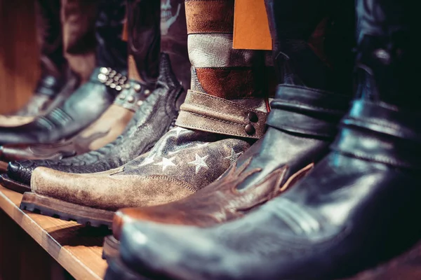 Uitgelijnde cowboys laarzen op een plank in een winkel — Stockfoto