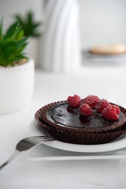 Beyaz arka planda ahududu olan çikolatalı pasta.