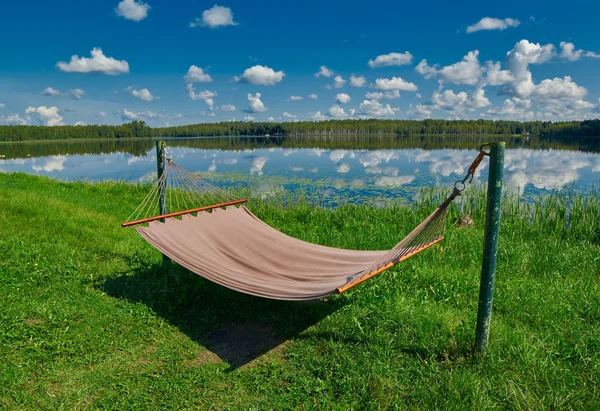 Relaxační houpací síť na břehu jezera pod letní sluníčko — Stock fotografie