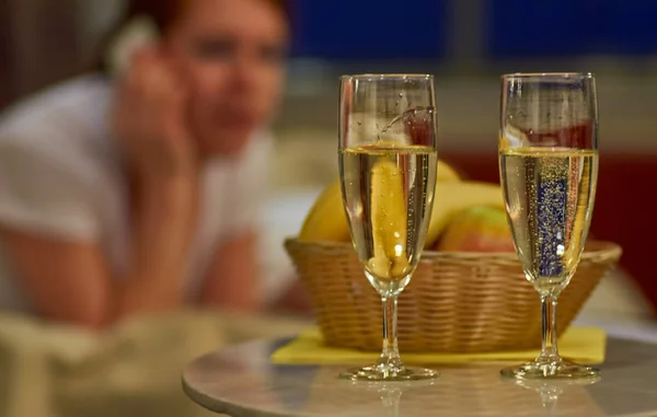 Two glasses of sparkling wine in hotel room with woman in background — Stock Photo, Image