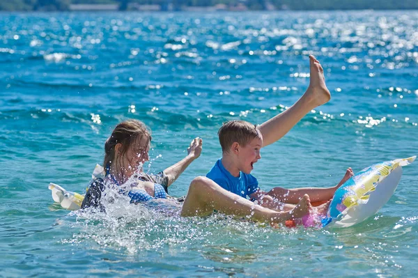 Enfants heureux jouant avec matelas en mer — Photo