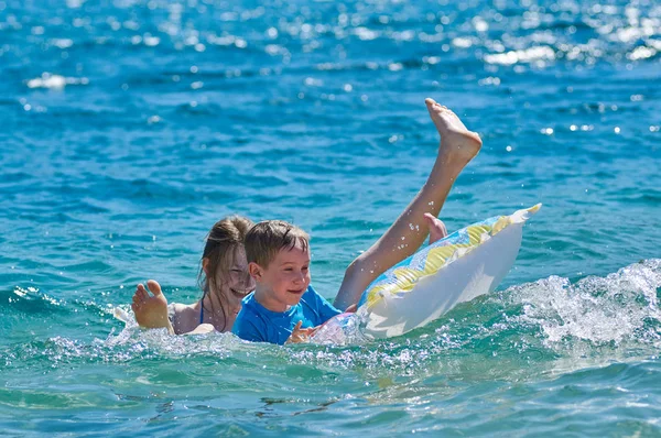 Enfants heureux jouant avec matelas en mer — Photo