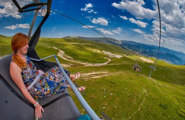 Genç Kızıl saçlı kadının açık hava bir teleferik bir yolculuk 