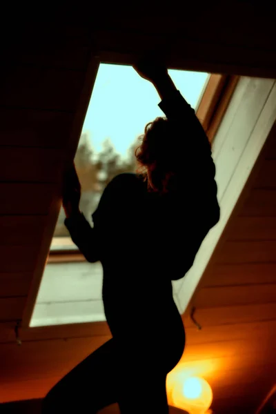 Νεαρή γυναίκα σιλουέτα κοντά σε παράθυρο σε σκοτεινή κρεβατοκάμαρα — Φωτογραφία Αρχείου