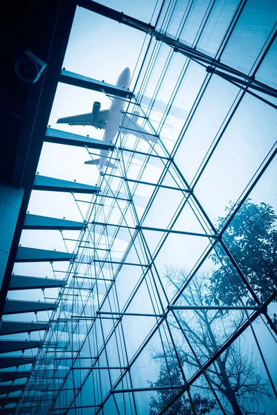 Airplane above the glass building — Stock Photo, Image