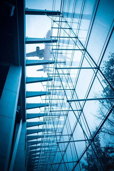 Flugzeug über dem Glasgebäude — Stockfoto