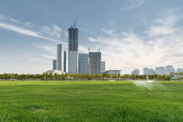 Green lawn with new city in construction — Stock Photo, Image