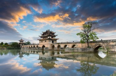 double dragon bridge in sunset on jianshui ancient city, is one of the famous monuments in yunnan province, China clipart
