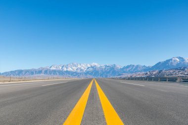 Xinjiang 'daki güzel doğal manzara, kanyon yakınındaki otoyol, kar dağına uzanan uzun yol.