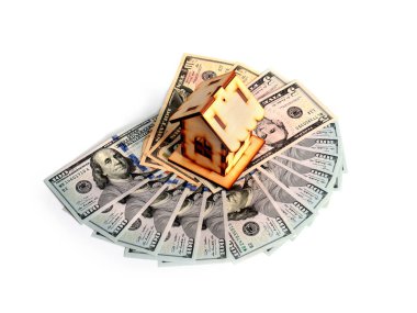 Tahta bir ev ve bir deste Amerikan kağıdı zenginliğin sembolü olarak dolarları gösteriyor.