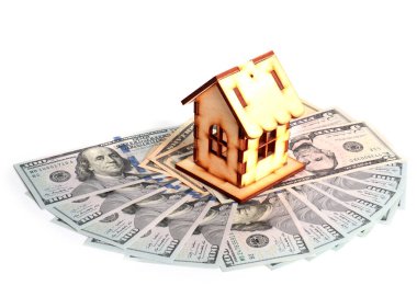 Tahta bir ev ve bir deste Amerikan kağıdı zenginliğin sembolü olarak dolarları gösteriyor.