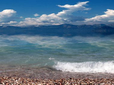 Bulutlu gökyüzü bir çakıl taşının üzerinde denizin kenarında