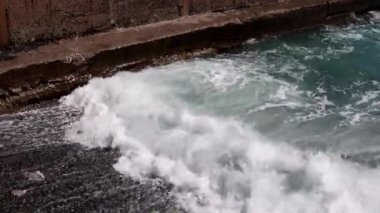 Deniz dalgaları kıyı dalgalarında kırılır ve kayalık bir plaja düşer.