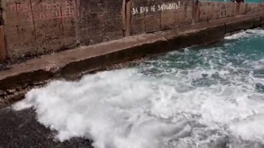 Deniz dalgaları kıyı dalgalarında kırılır ve kayalık bir plaja düşer.