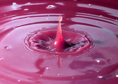 Sıvının yüzeyine bir damla su düşer ve renkli desenler oluşturur.