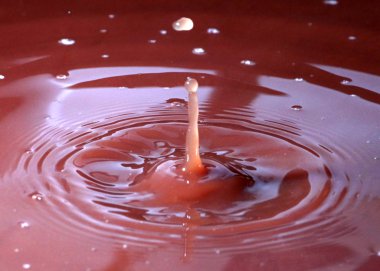 Sıvının yüzeyine bir damla su düşer ve renkli desenler oluşturur.