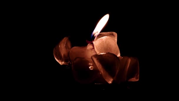 la flamme vive d'une bougie de cire entourée de glace d'eau transparente 