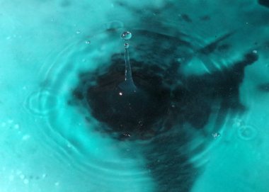 Bir sıvı damlası suyun yüzeyine düşer.