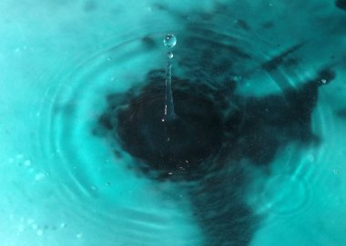 Bir sıvı damlası suyun yüzeyine düşer.