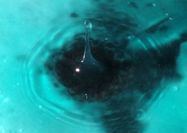 Bir sıvı damlası suyun yüzeyine düşer.