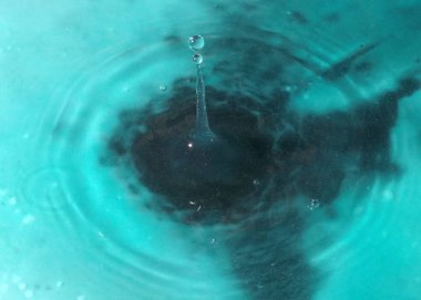 Bir sıvı damlası suyun yüzeyine düşer.