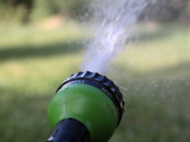 a stream of clean water flows through a plastic sprayer when watering the lawn