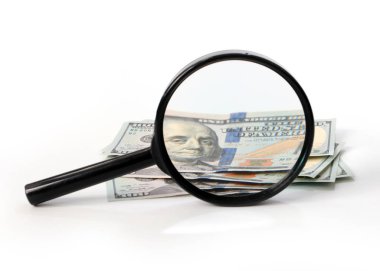 a large magnifying glass and a bunch of paper American dollars