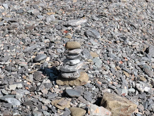 a pyramid of stones stands on a pebble beach as a symbol of balanced peace of mind