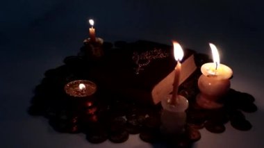 Mum ışığı ve altın haç ve zincirli eski bir kitap.