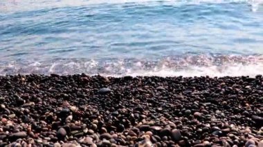 Sahilde kum ve çakıl taşı kumsalı ve deniz dalgaları