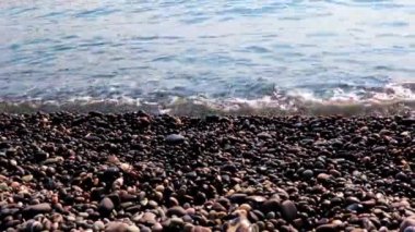 Sahilde kum ve çakıl taşı kumsalı ve deniz dalgaları