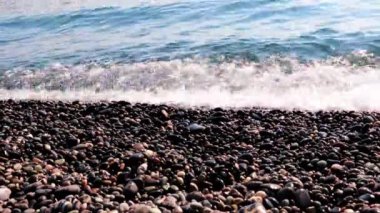 Sahilde kum ve çakıl taşı kumsalı ve deniz dalgaları