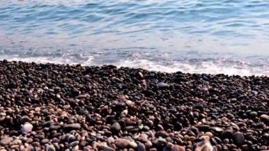 Sahilde kum ve çakıl taşı kumsalı ve deniz dalgaları