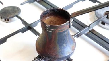 Mutfaktaki gaz sobasının üzerinde eski bir metal kahve makinesinde koyu sade kahve yapmak.