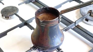 Mutfaktaki gaz sobasının üzerinde eski bir metal kahve makinesinde koyu sade kahve yapmak.