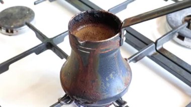 Mutfaktaki gaz sobasının üzerinde eski bir metal kahve makinesinde koyu sade kahve yapmak.