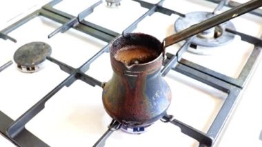 Mutfaktaki gaz sobasının üzerinde eski bir metal kahve makinesinde koyu sade kahve yapmak.