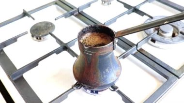 Mutfaktaki gaz sobasının üzerinde eski bir metal kahve makinesinde koyu sade kahve yapmak.
