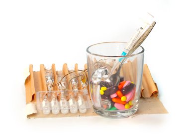 Bir bardak dolusu hap, ampul ve enjeksiyon için şırınga.