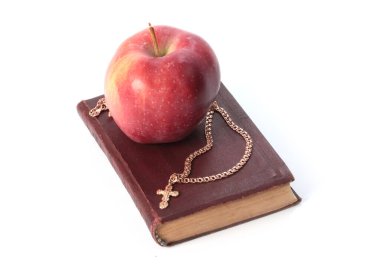 Olgun kırmızı bir elma ve altın haçlı dini bir kitap.